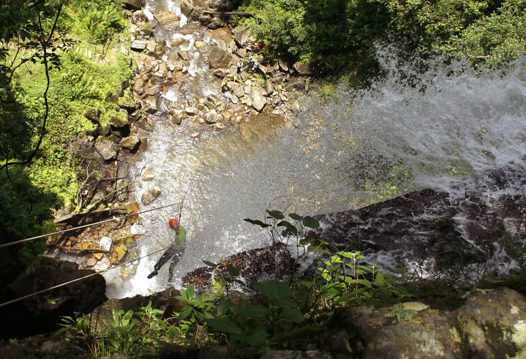 Praticante de rapel descendo paredão rochoso no PETAR